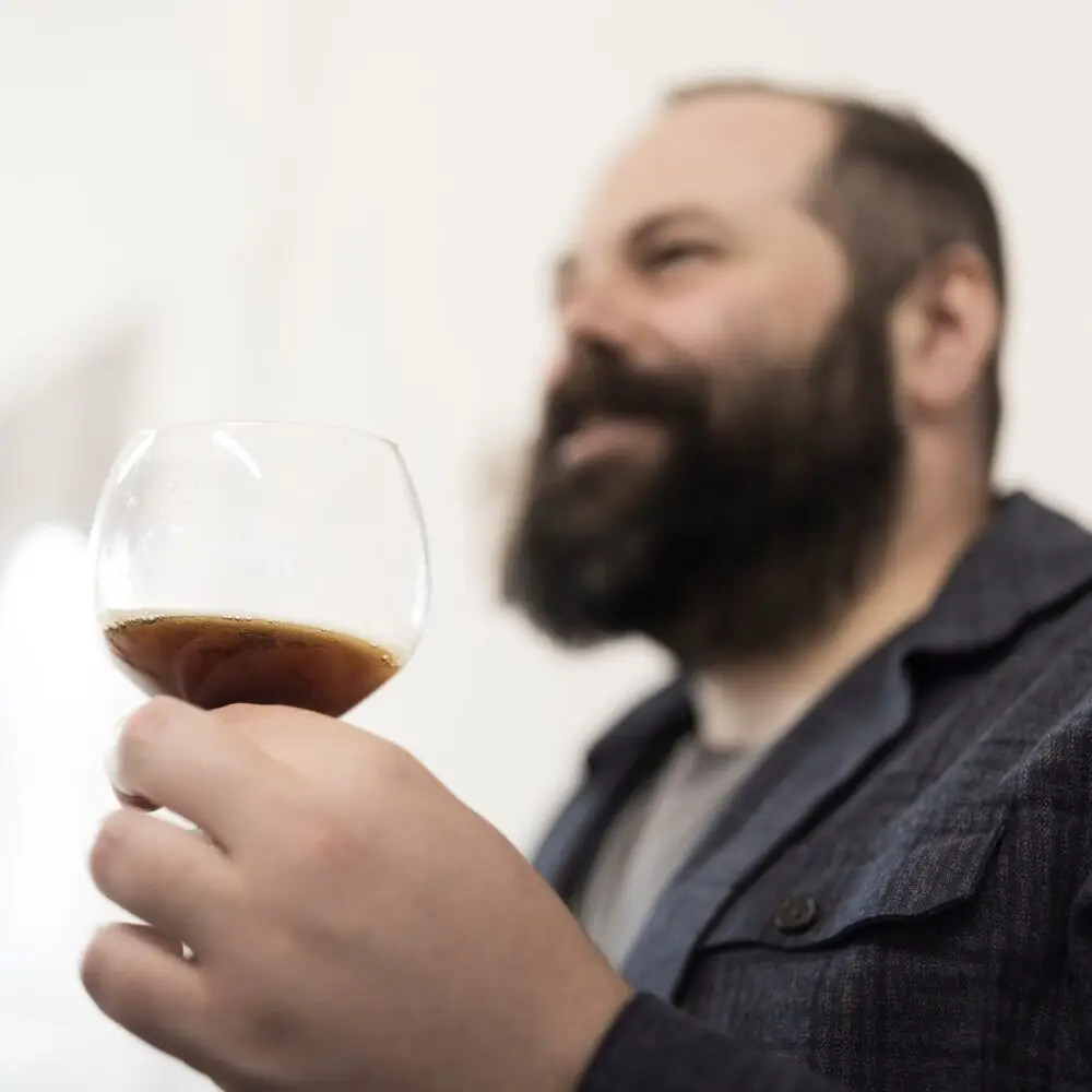 Man holding glass of Tynt Meadow and smiling during Mount St Bernard Abbey Brewery Tour