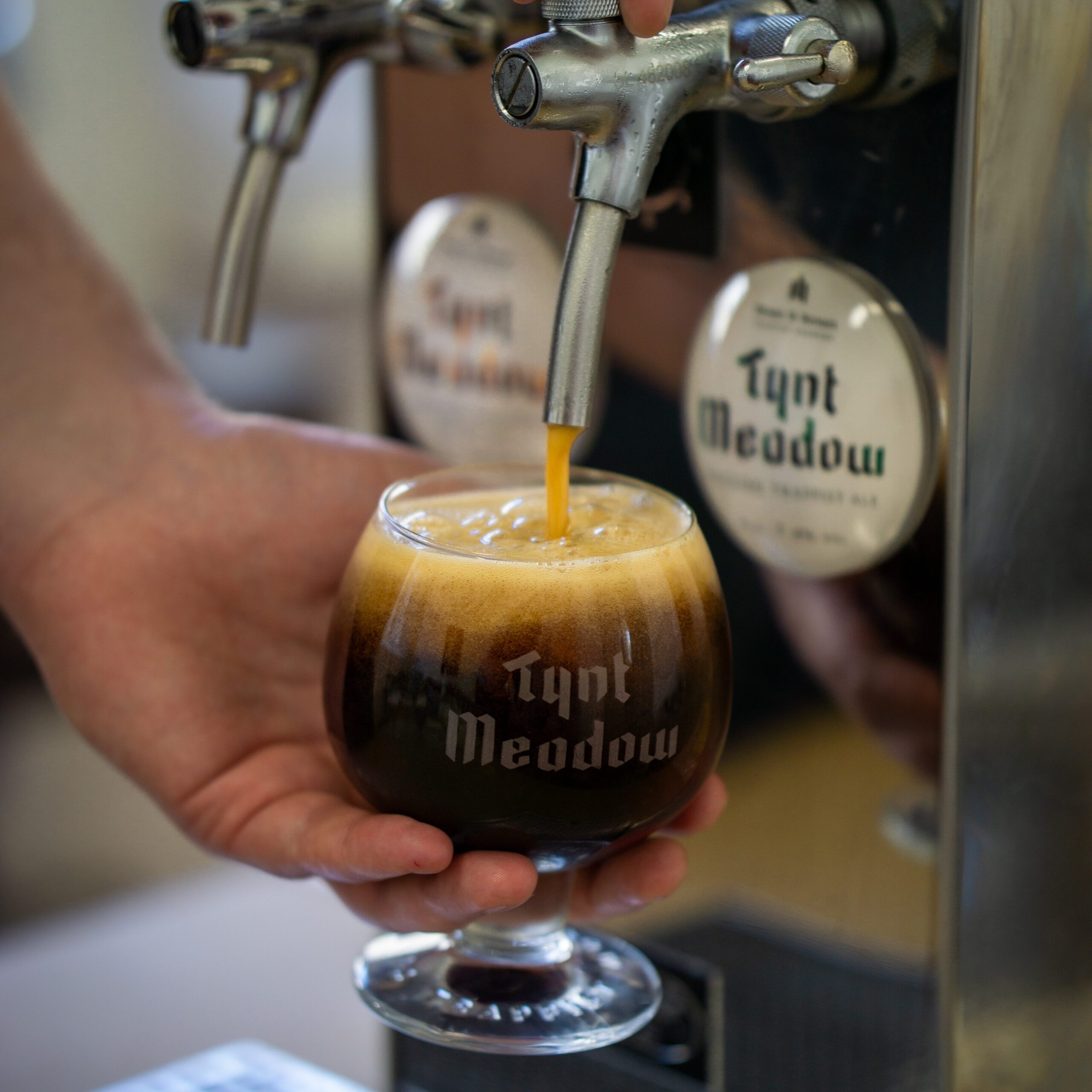Tynt Meadow Trappist ale being poured from a draught tap into a branded glass