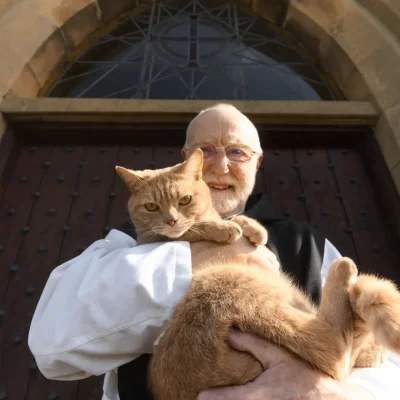 Monk of Mount St Bernard holding Leo the cat and smiling