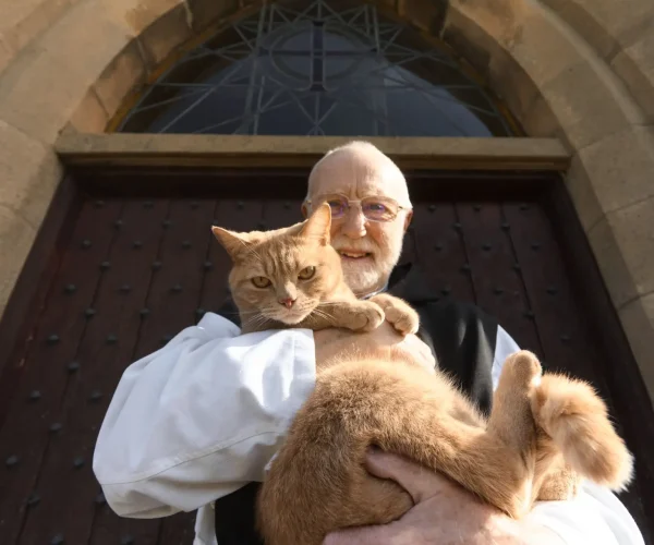 Monk of Mount St Bernard holding Leo the cat and smiling